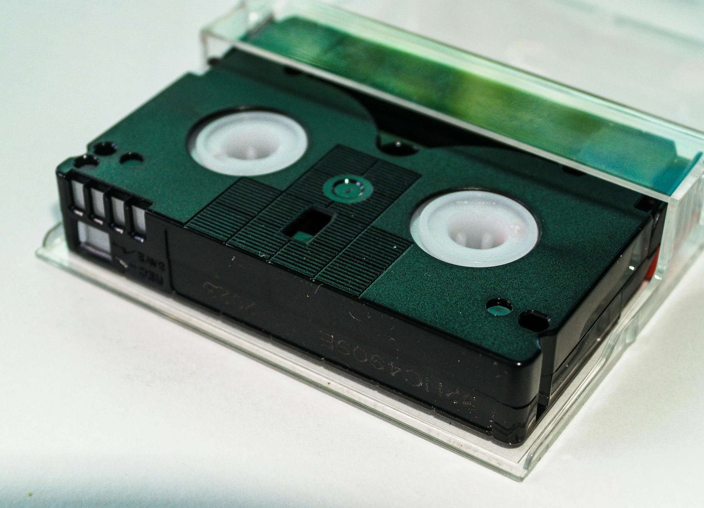 a close up of a cassette on a table, by Adam Marczyński, unsplash, video art, holographic case display, set against a white background, greenish expired film, used tape