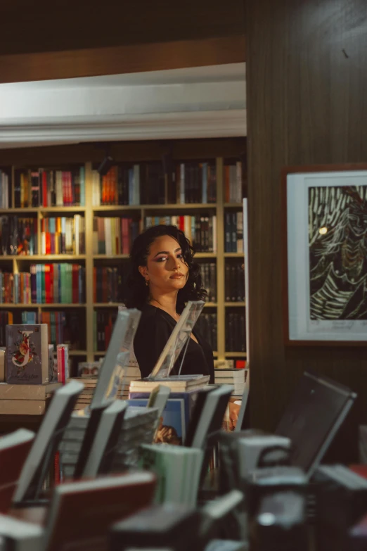 a woman standing in front of a bookshelf in a library, a portrait, by Julia Pishtar, pexels contest winner, portait of haifa wehbe, a propaganda, official store photo, books cave