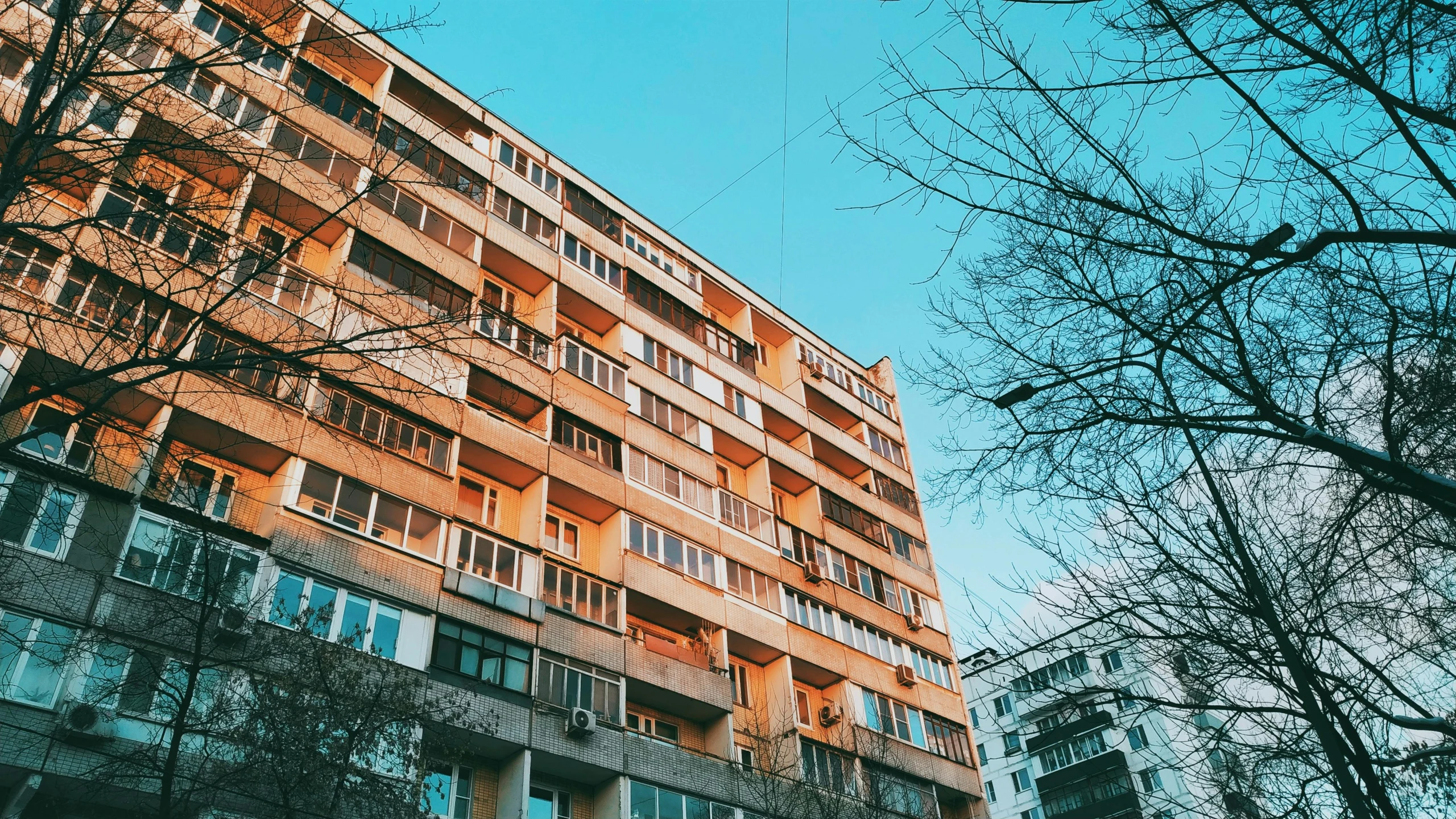 a tall building sitting in the middle of a city, by Emma Andijewska, unsplash contest winner, brutalism, soviet apartment buildings, 🪔 🎨;🌞🌄, sunfaded, 3 4 5 3 1