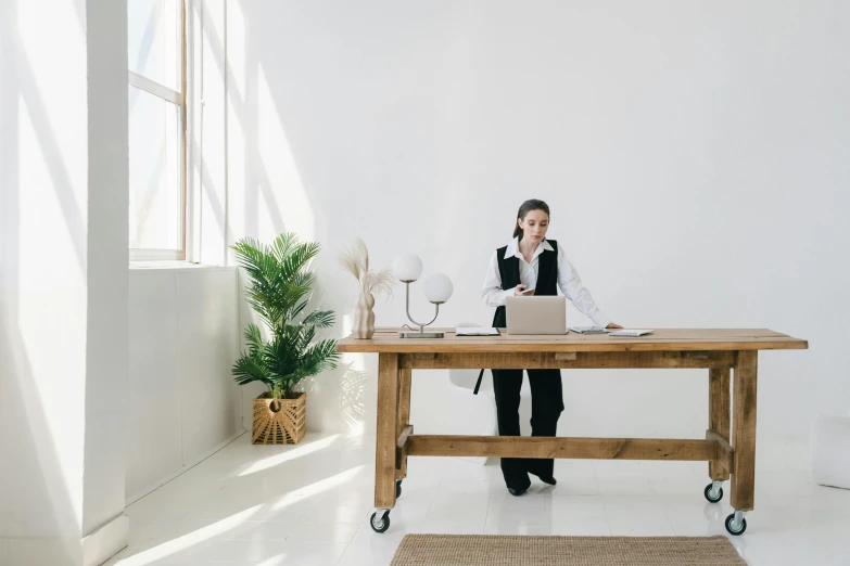 a man sitting at a desk talking on a cell phone, pexels contest winner, minimalism, standing on a desk, young business woman, long table, sustainable materials