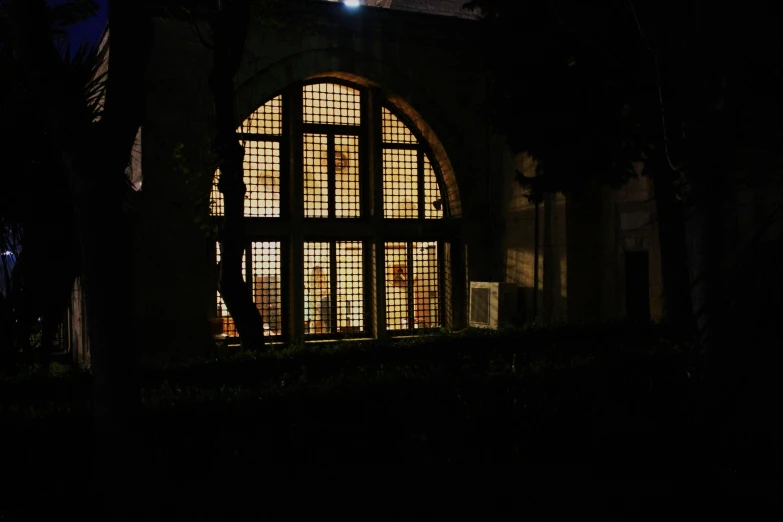 a window in a building lit up at night, mausoleum, from the distance, studio ghiblil, biennale