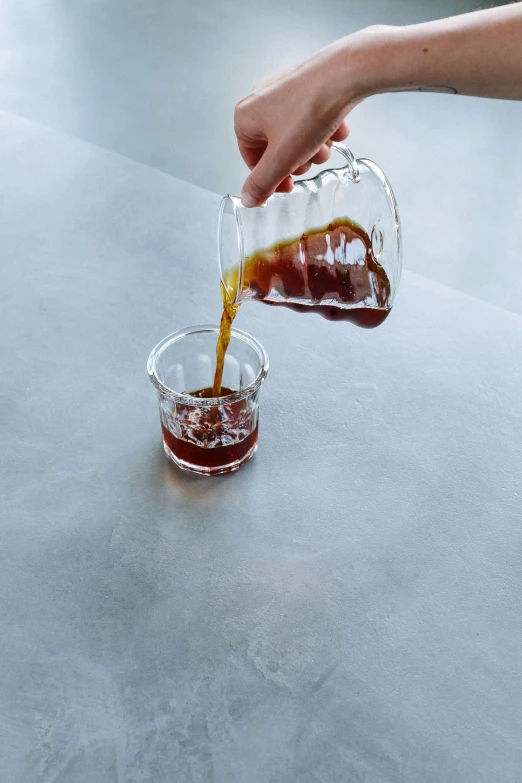 a person pouring syrup into a glass on a table, detailed product image, cold brew coffee ), medium format, glassware