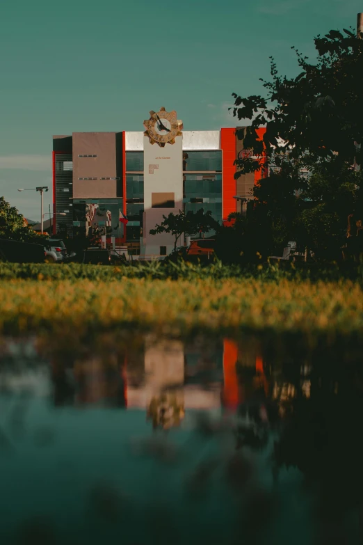 a large building sitting on top of a lush green field, pexels contest winner, modernism, red reflections, at college, cinematic image, lagoon