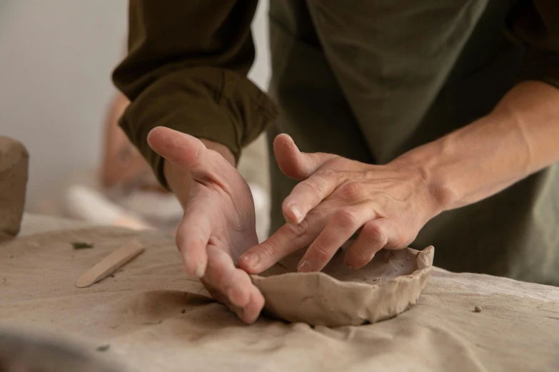 a close up of a person making a clay object, by Fuller Potter, indi creates, plated arm, folded, magic