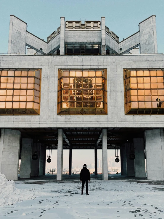 a person standing in front of a building in the snow, by Julia Pishtar, pexels contest winner, brutalism, located in hajibektash complex, giant crypto vault, frontal view, golden windows