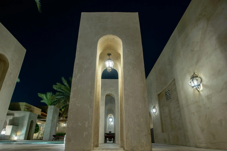the inside of a building lit up at night, inspired by Ricardo Bofill, pexels contest winner, art nouveau, jeddah city street, tall arched stone doorways, calm evening, brutalist courtyard