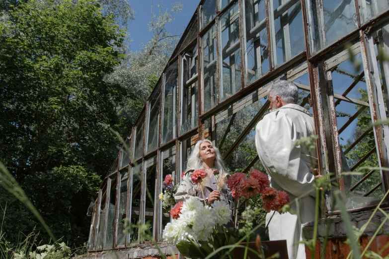 a man and a woman standing in front of a building, holy ceremony, greenhouse, 15081959 21121991 01012000 4k, anna nikonova