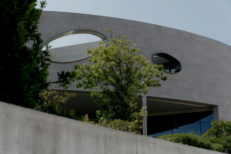 a man riding a skateboard on top of a cement wall, inspired by Tadao Ando, circular windows, seen from a distance, cupertino, freddy mamani silvestre facade