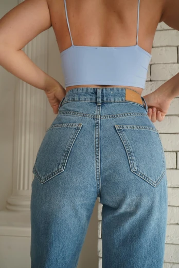 a woman standing in front of a brick wall, inspired by Jean Hey, trending on pexels, baggy jeans, back view », pale blue, 90s photo