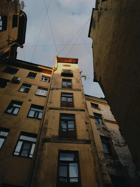 a tall building sitting in the middle of a city, inspired by Elsa Bleda, pexels contest winner, graffiti, lviv, low quality photo, wires hanging across windows, low angle photo