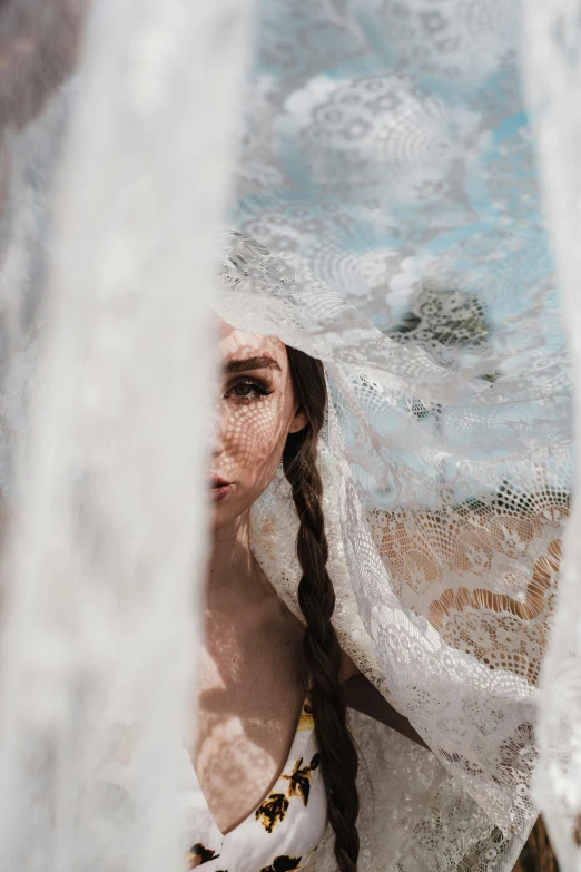 a woman in a white dress with a veil over her head, inspired by Elsa Bleda, unsplash contest winner, underwater face, dressed in a frilly ((lace)), wet drapery, woman with braided brown hair