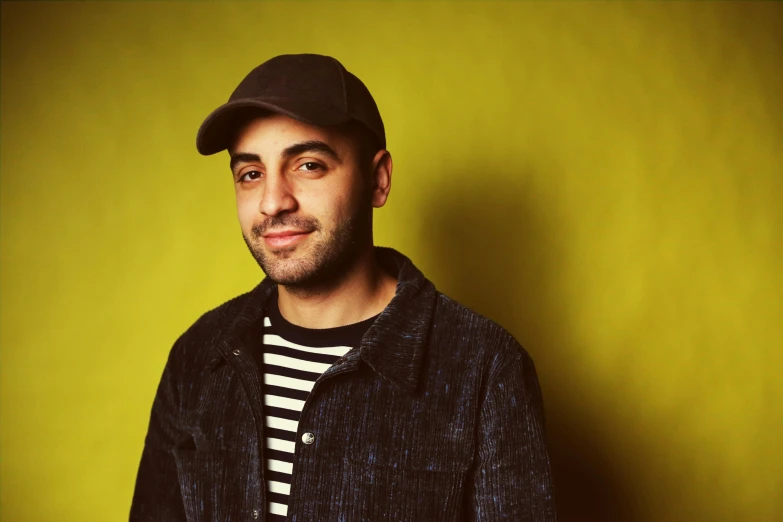 a man standing in front of a yellow wall, an album cover, inspired by Nadim Karam, pexels contest winner, photorealism, smiling slightly, in front of a black background, reza afshar, corinne day