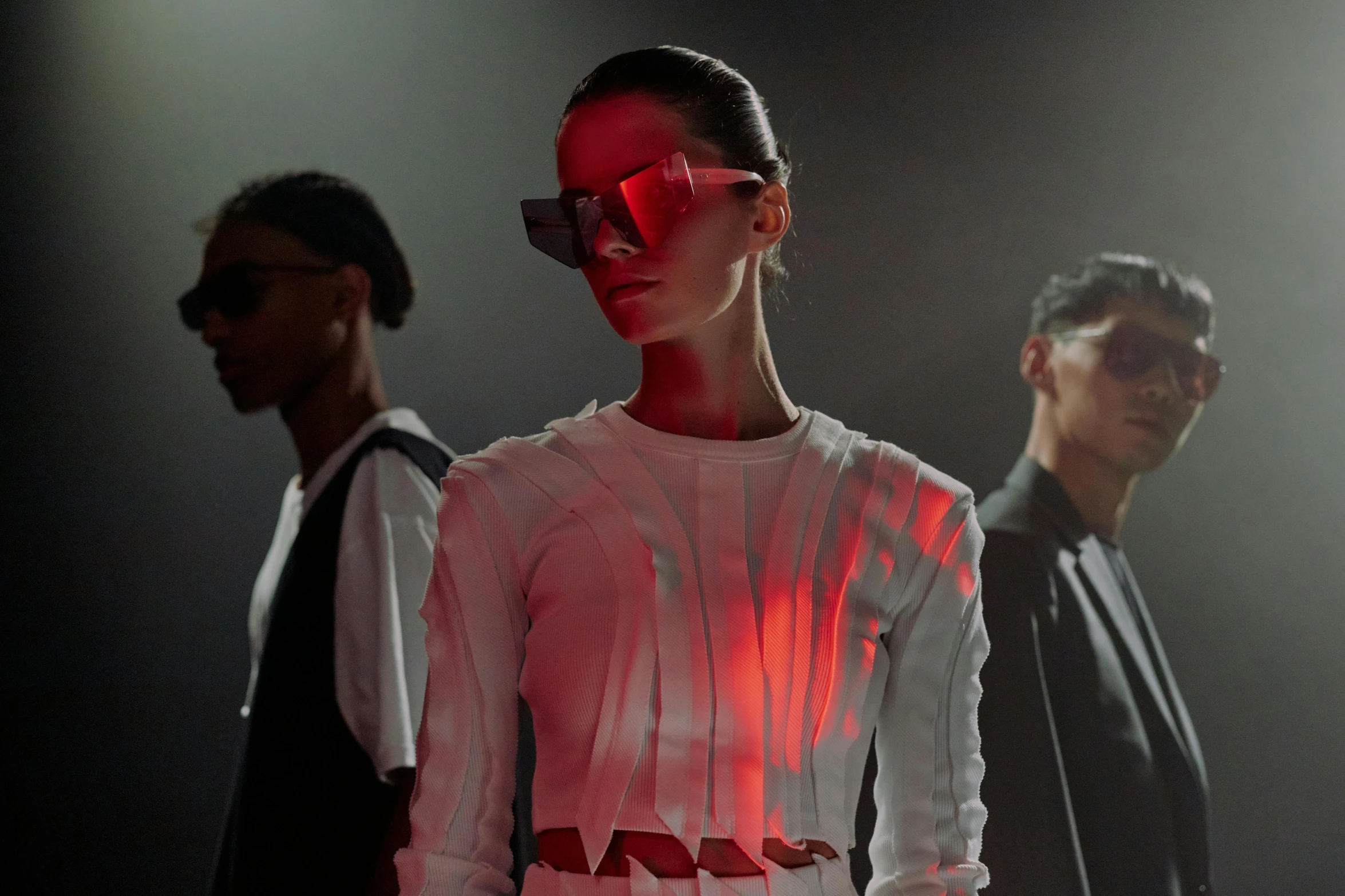 a couple of people standing next to each other, a digital rendering, trending on unsplash, bauhaus, girl at a fashion show in hell, red reflective lens, fashion studio lighting, implanted sunglasses