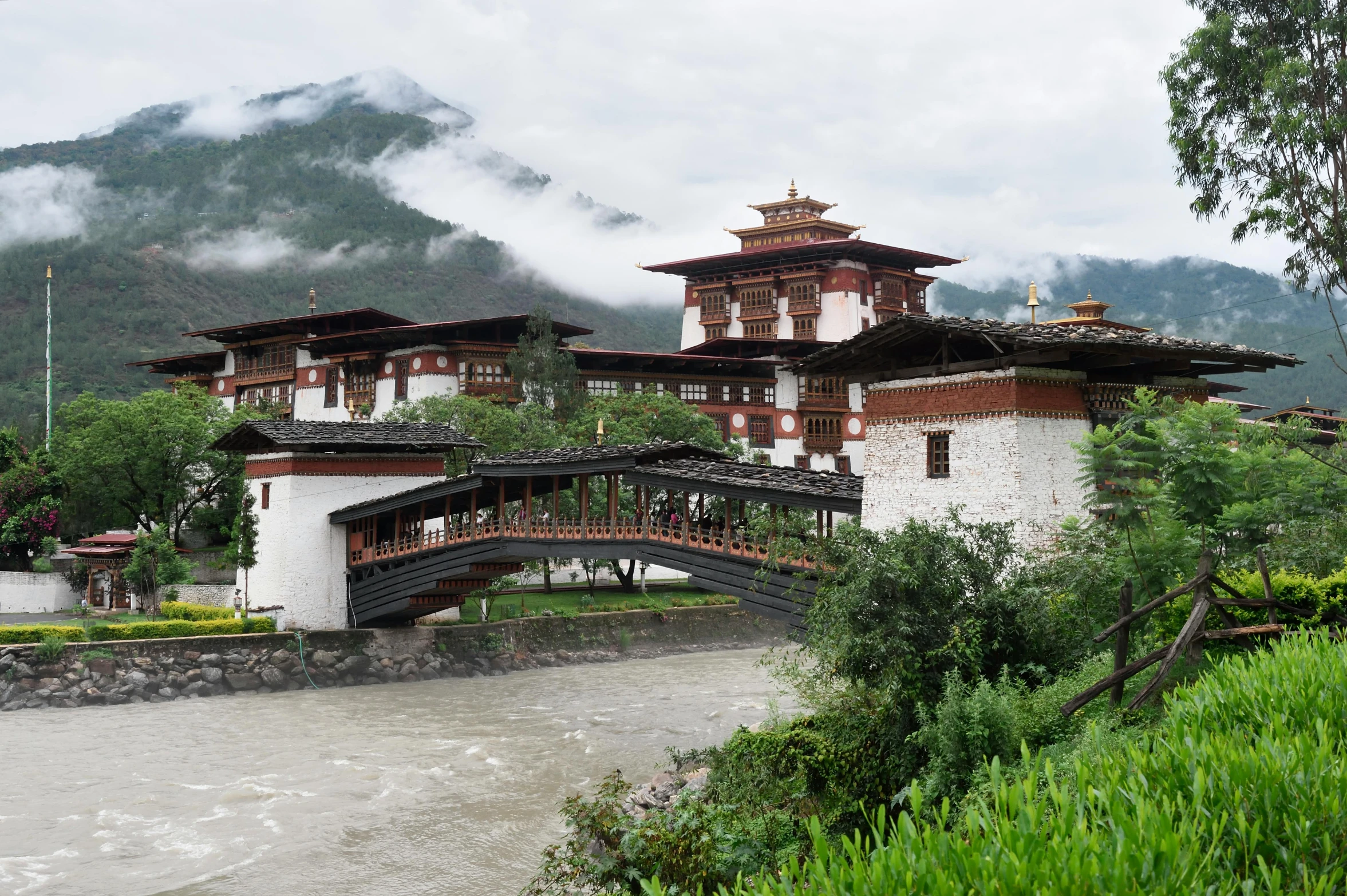 a bridge over a river in front of a building, inspired by Steve McCurry, pexels contest winner, hurufiyya, bhutan, square, white, grand majestic mountains