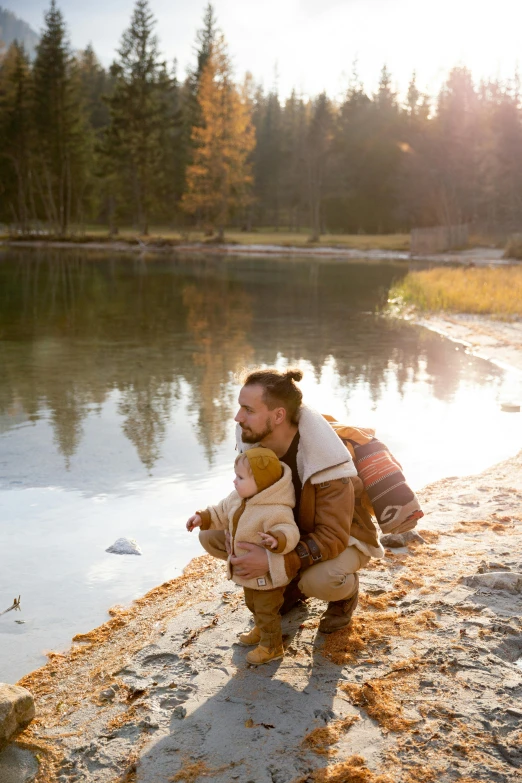 a woman holding a child near a body of water, hipster dad, lumberjack, profile image, leather clothing and boots