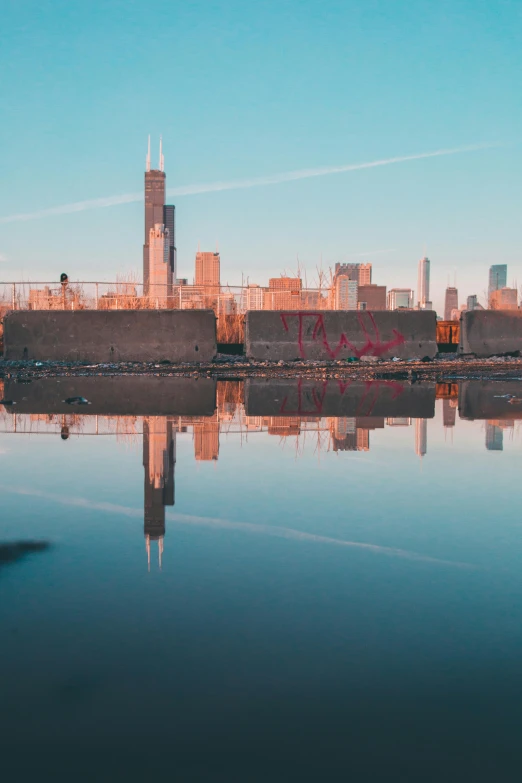 a large body of water with a city in the background, by Jacob Burck, unsplash contest winner, graffiti, reflective gradient, chicago, ruins around, morning light