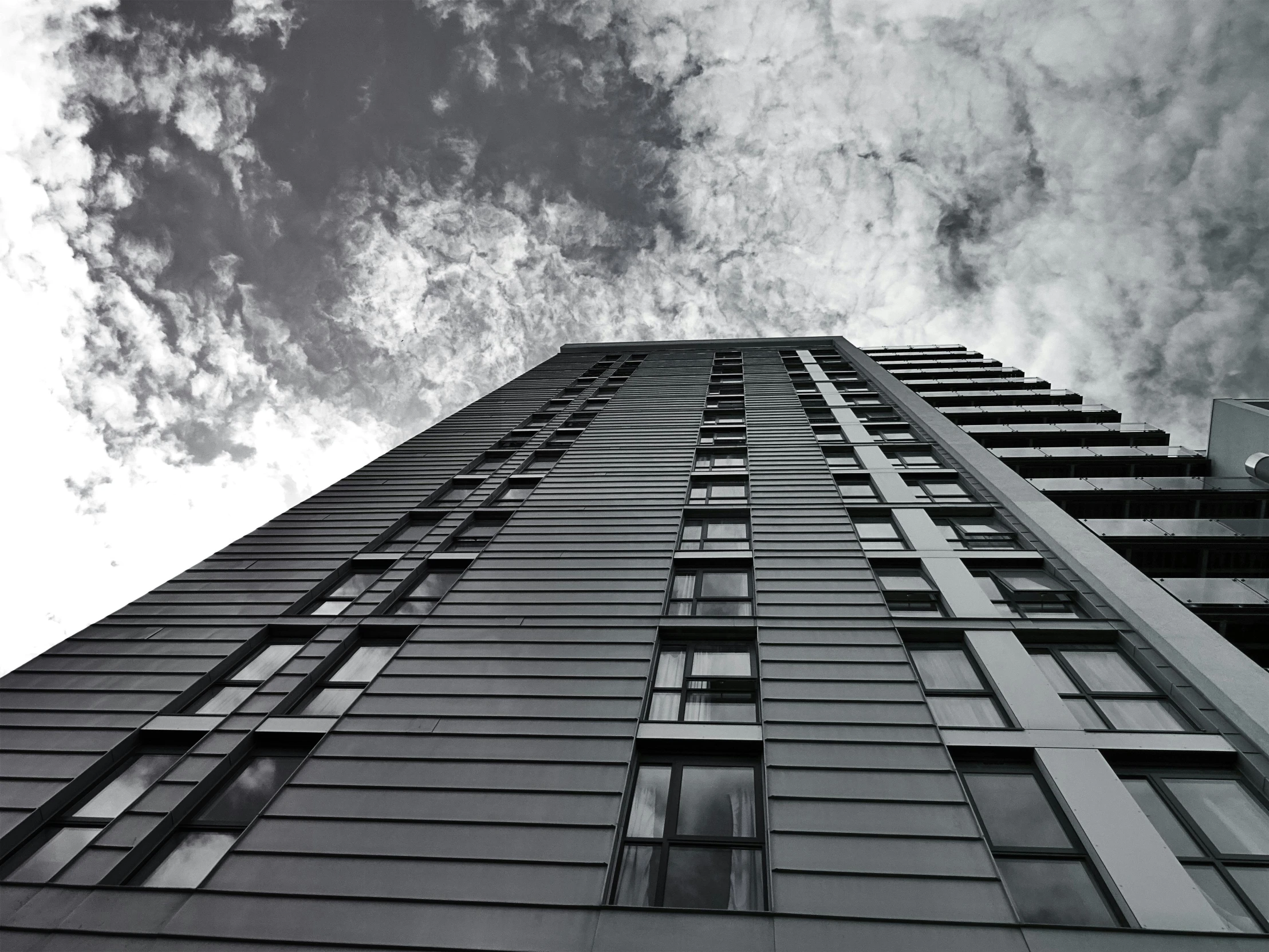 a black and white photo of a tall building, inspired by Thomas Struth, pexels contest winner, grey clouds, iron cladding, photo high definition, blue sky