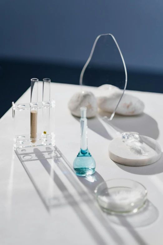 a couple of glasses sitting on top of a table, experimenting in her science lab, product display, blue, rituals