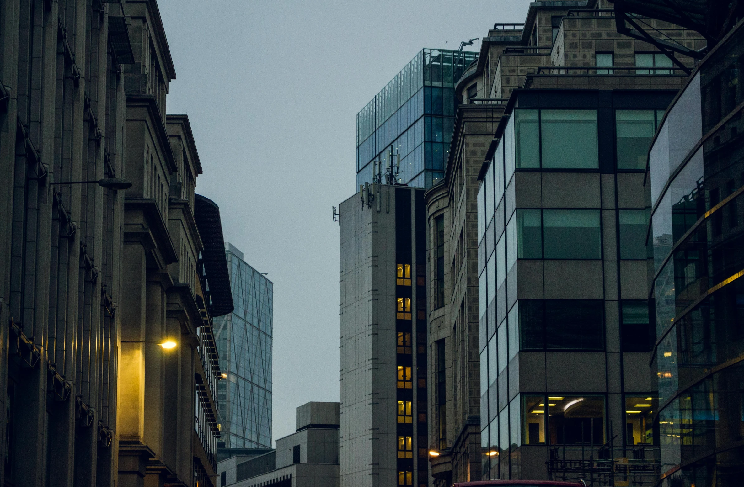 a red double decker bus driving down a city street, a photo, inspired by Richard Wilson, pexels contest winner, brutalism, city street at dusk, grey, overwatch building, glass and steel