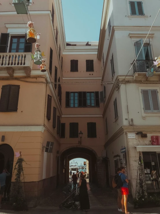 a group of people walking down a street next to tall buildings, an album cover, pexels contest winner, renaissance, capri coast, with archways, low quality photo, view from inside