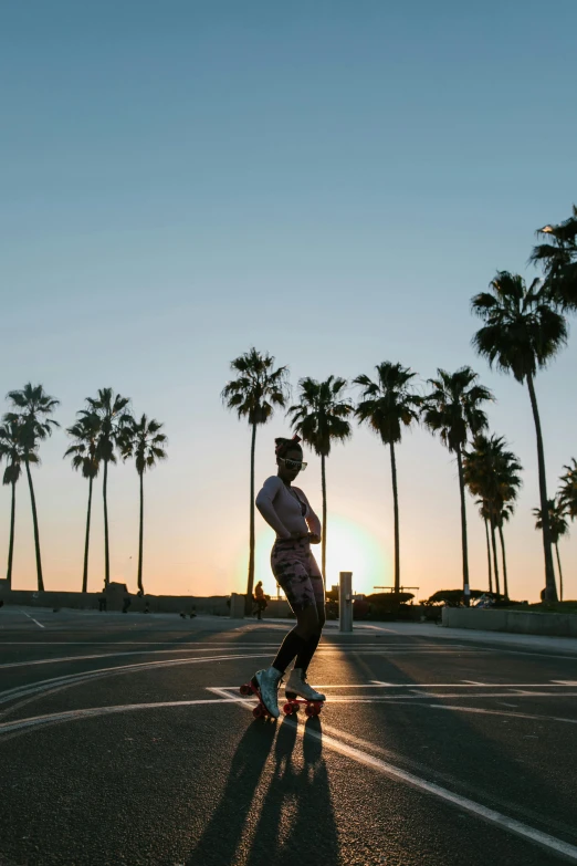 a man riding a skateboard down a street next to palm trees, unsplash contest winner, sun behind her, rollerskaters, profile image, overlooking