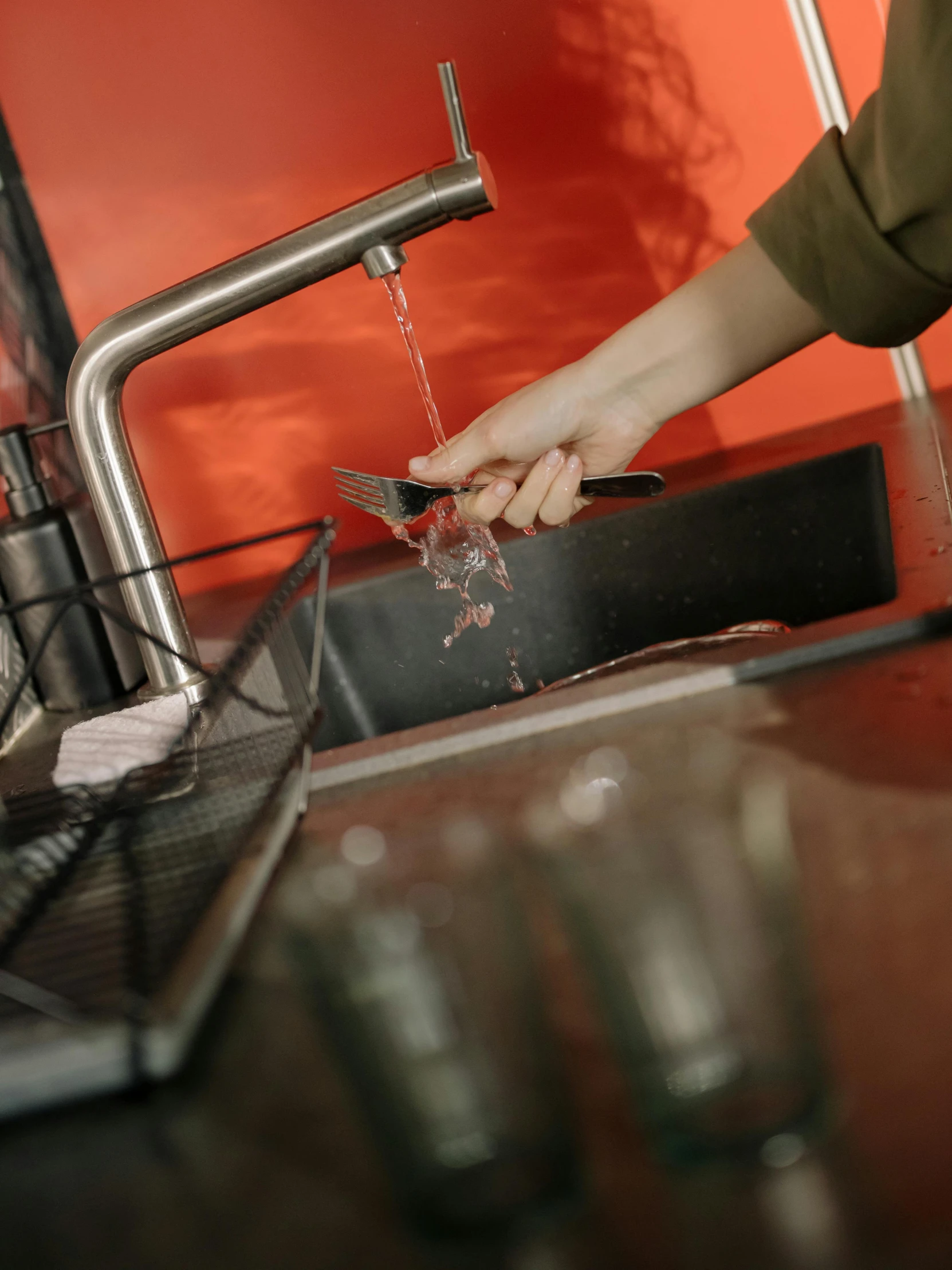 a woman washing her hands in a kitchen sink, by Adriaen Hanneman, pexels contest winner, spilling juice, stainless steal, promo image, levers