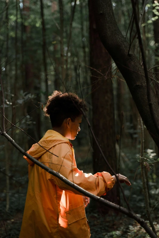 a woman in an orange jacket walking through a forest, unsplash contest winner, visual art, portrait of willow smith, pondering, ((forest)), forest picnic