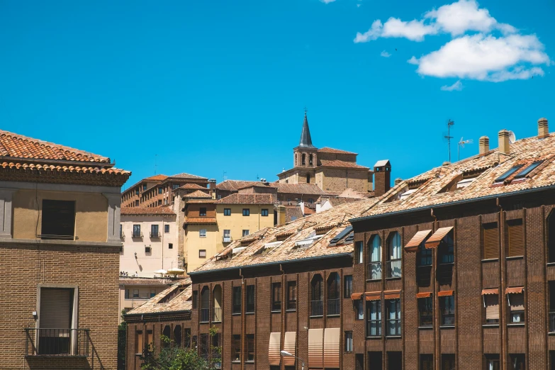 a couple of buildings that are next to each other, inspired by Lajos Berán, pexels contest winner, teruel city in 1989, clear blue skies, hiding in the rooftops, brown