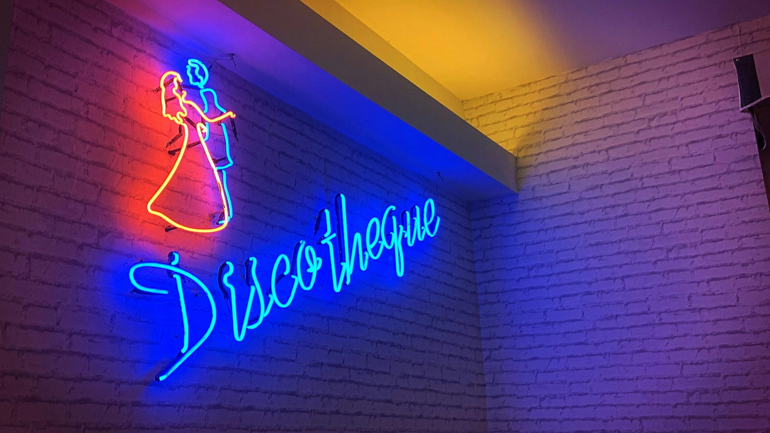 a neon sign on the side of a brick wall, an album cover, by Robbie Trevino, dribble, arabesque, rgb wall light, des boutiques avec des neons, nightclub dancing inspired, profile image