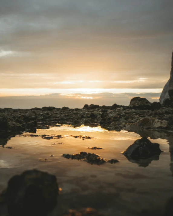 a bride and groom standing on a rocky beach at sunset, by Sebastian Spreng, unsplash contest winner, minimalism, rainbow reflection, sitting in a reflective pool, photo of shiprock, abel tasman