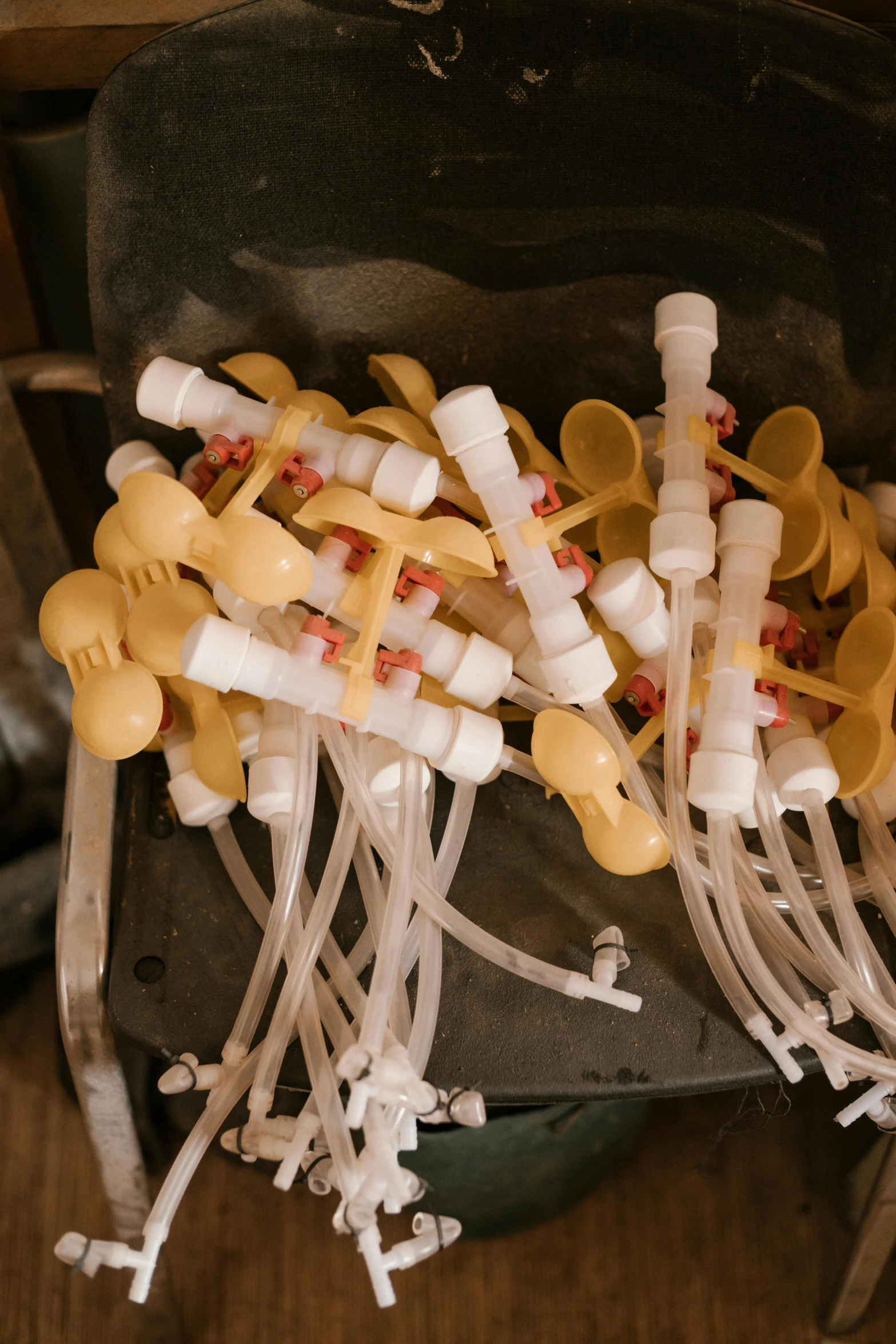 a bunch of plastic spoons sitting on top of a chair, with an iv drip, pipes and valves, intricate wet latex suspenders, six packs