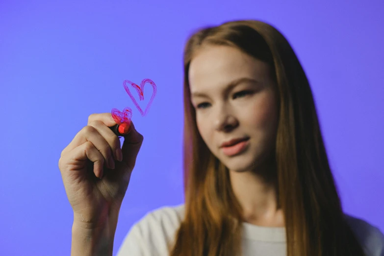 a woman holding a marker with a heart drawn on it, trending on pexels, purple and blue neons, teenager girl, product introduction photo, portrait sophie mudd