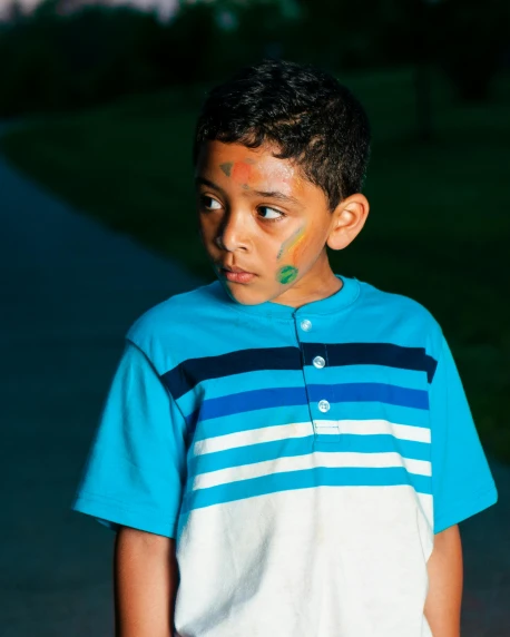 a young boy holding a skateboard on a sidewalk, inspired by Jan Rustem, day - glow face paint, ( ( dark skin ) ), blue and green light, looking sad