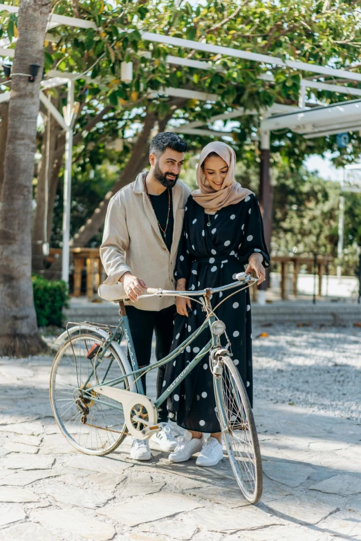 a man and a woman standing next to a bicycle, pexels contest winner, muslim, casual modern clothing, lush surroundings, restoration