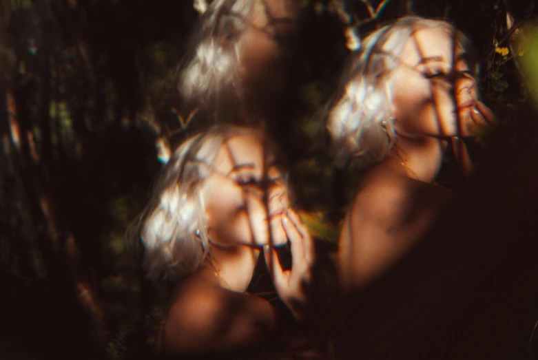 a couple of women standing next to each other, inspired by Elsa Bleda, trending on pexels, surrealism, close up of a blonde woman, mirrored, hides in the shadows of trees, blurry image