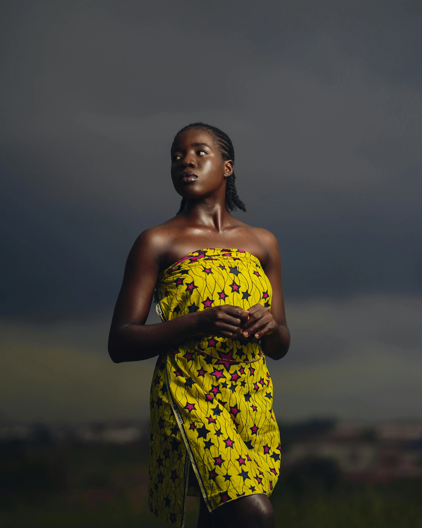 a woman in a yellow dress standing in a field, dark skin tone, on a rooftop, dramatic press photo, photographed for reuters