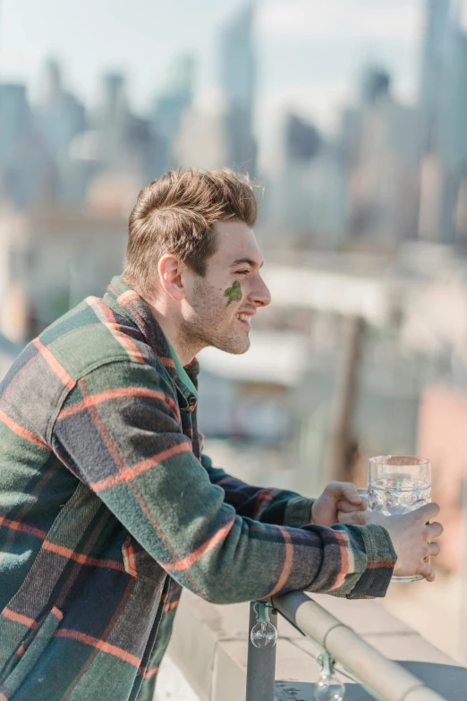 a man standing on top of a roof holding a glass of water, a portrait, trending on unsplash, mac miller, markings on his face, humans of new york style, happy cozy feelings