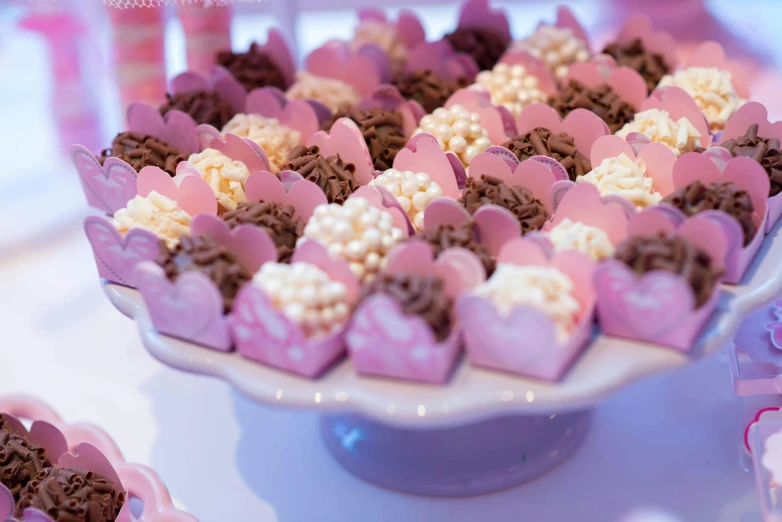 a close up of a plate of cupcakes on a table, pink arches, fully chocolate, many hearts, sea of parfait