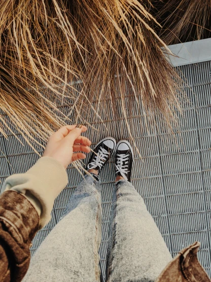 a person standing on top of a metal floor, dried palmtrees, 8k selfie photograph, wearing red converse shoes, on a canva