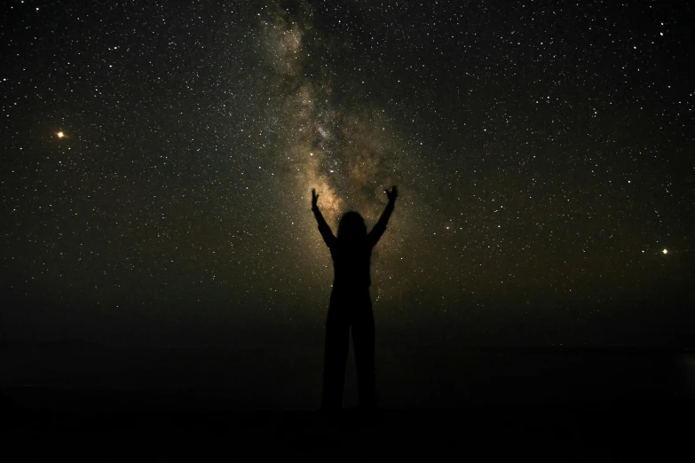 a person standing on top of a hill under a sky full of stars, pexels contest winner, light and space, arms held high in triumph, god is a woman, with a black dark background, brown