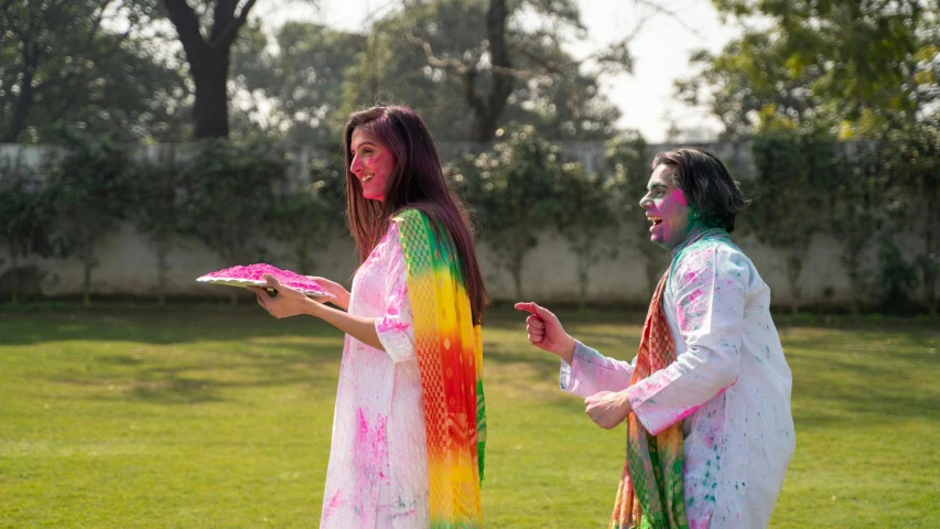 a couple of women standing on top of a lush green field, a colorized photo, pexels contest winner, color field, holi festival of rich color, wearing a kurta, wearing a colorful men's suit, covered in white flour