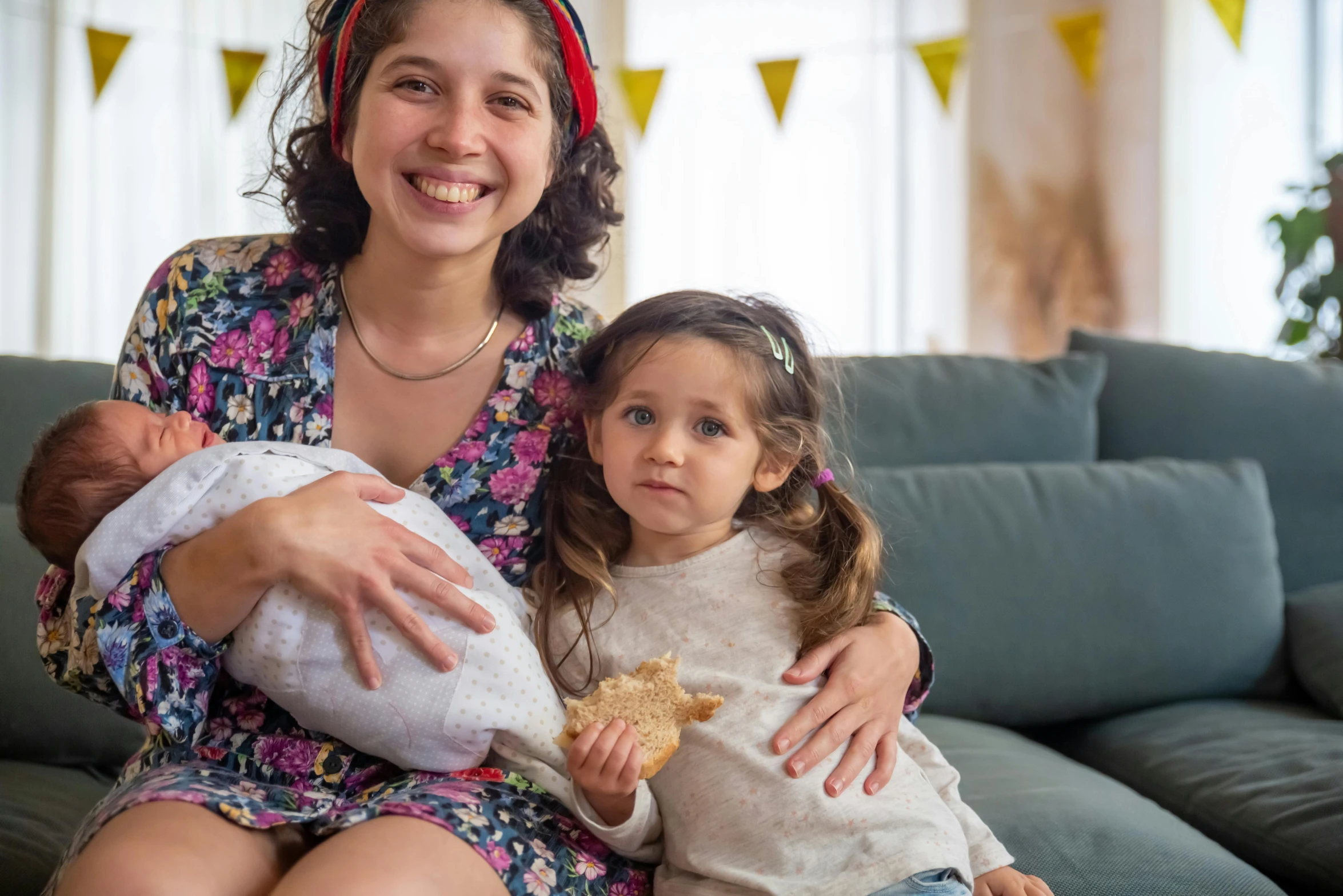 a woman sitting on a couch holding a baby, pexels contest winner, figuration libre, portrait image, chilean, holding mesh bag with bagels, big sister