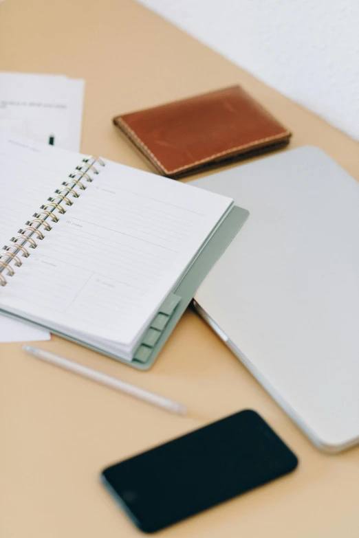 a white laptop computer sitting on top of a wooden desk, holding notebook, various items, plush leather pads, detailed product image