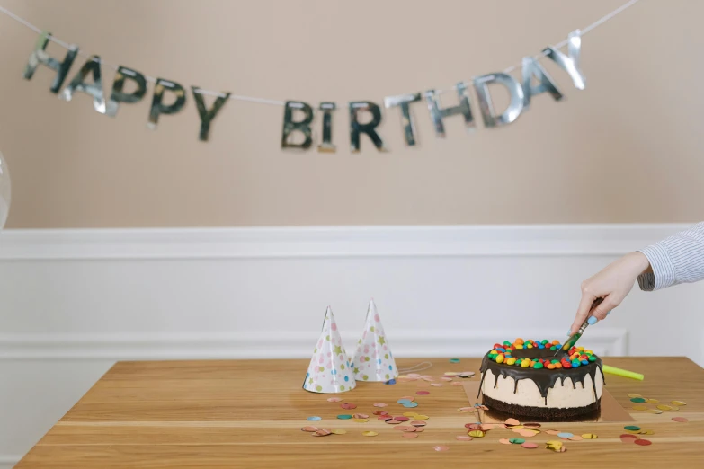 a person cutting a birthday cake with a knife, an album cover, by Julia Pishtar, pexels, happy kid, background image, decoration around the room, full body image