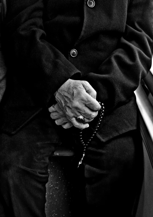 a black and white photo of a man sitting on a bench, symbolism, photo of a hand jewellery model, an old lady, prayer hands, dressed in black