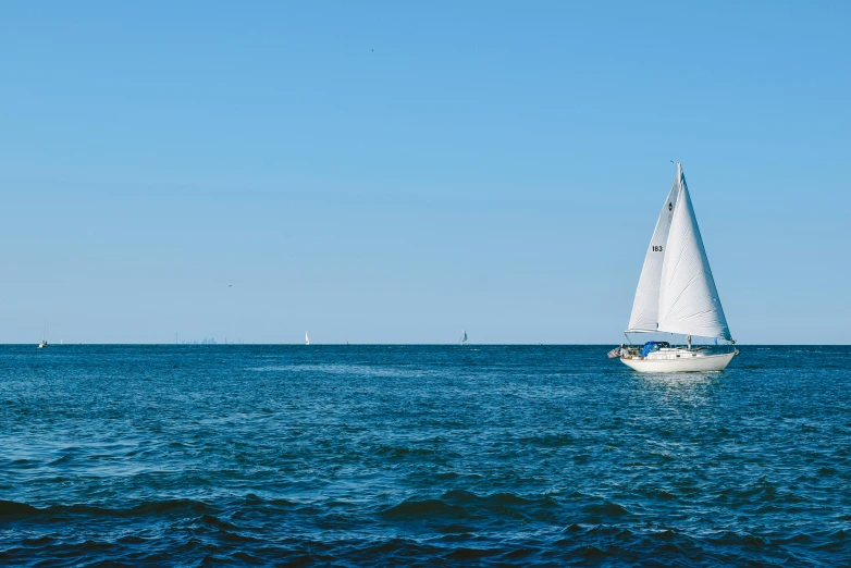 a sailboat in the middle of a large body of water, pexels contest winner, white and blue, from wheaton illinois, sea background, oceanside