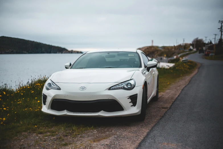 a white sports car parked on the side of a road, by Carey Morris, pexels contest winner, full front view, fan favorite, ae 8 6, accompany hybrid