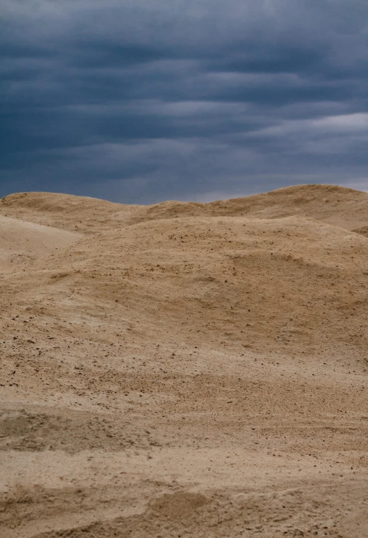 a man riding a surfboard on top of a sandy beach, by Matthias Stom, land art, craters, overcast, egyptian landscape, sparse detail