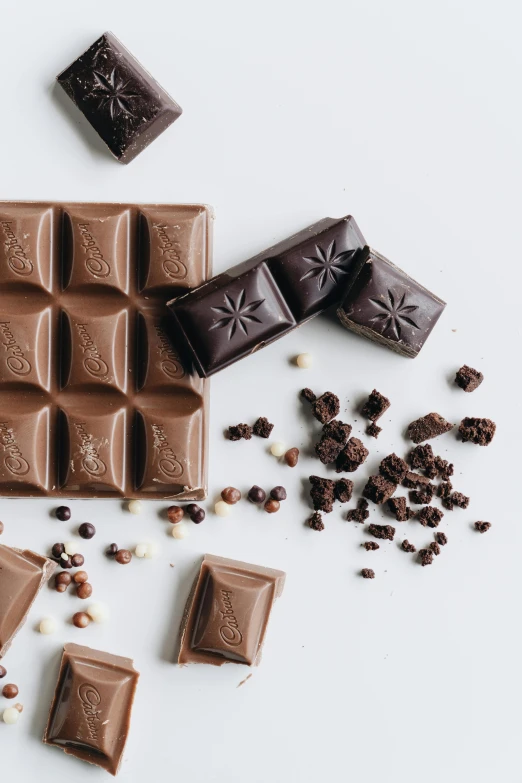 a white table topped with lots of chocolate, a still life, trending on pexels, embossed, 6 pack, smoky, squares