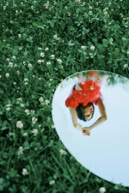 a woman laying in the grass in front of a mirror, inspired by Oleg Oprisco, unsplash, little planet, show, high quality picture, [ realistic photography ]